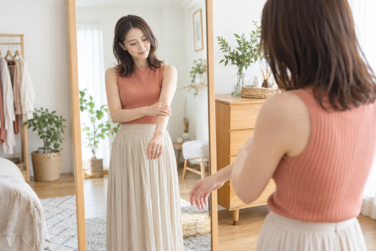 鏡の前で自分が手入れを楽にしたい腕の範囲を確かめる女性