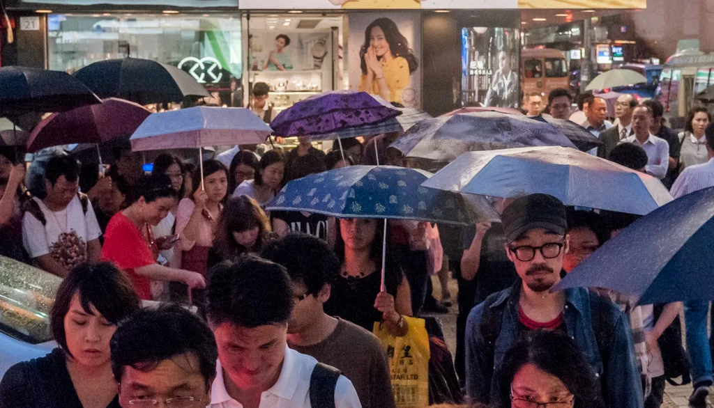 雨の香港で傘を差して歩く人々