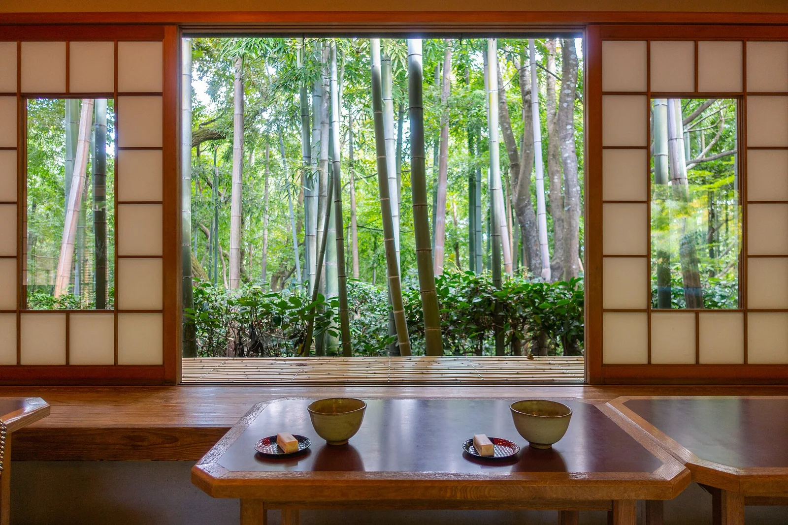 竹林を望む座敷の卓上に置かれた抹茶と菓子