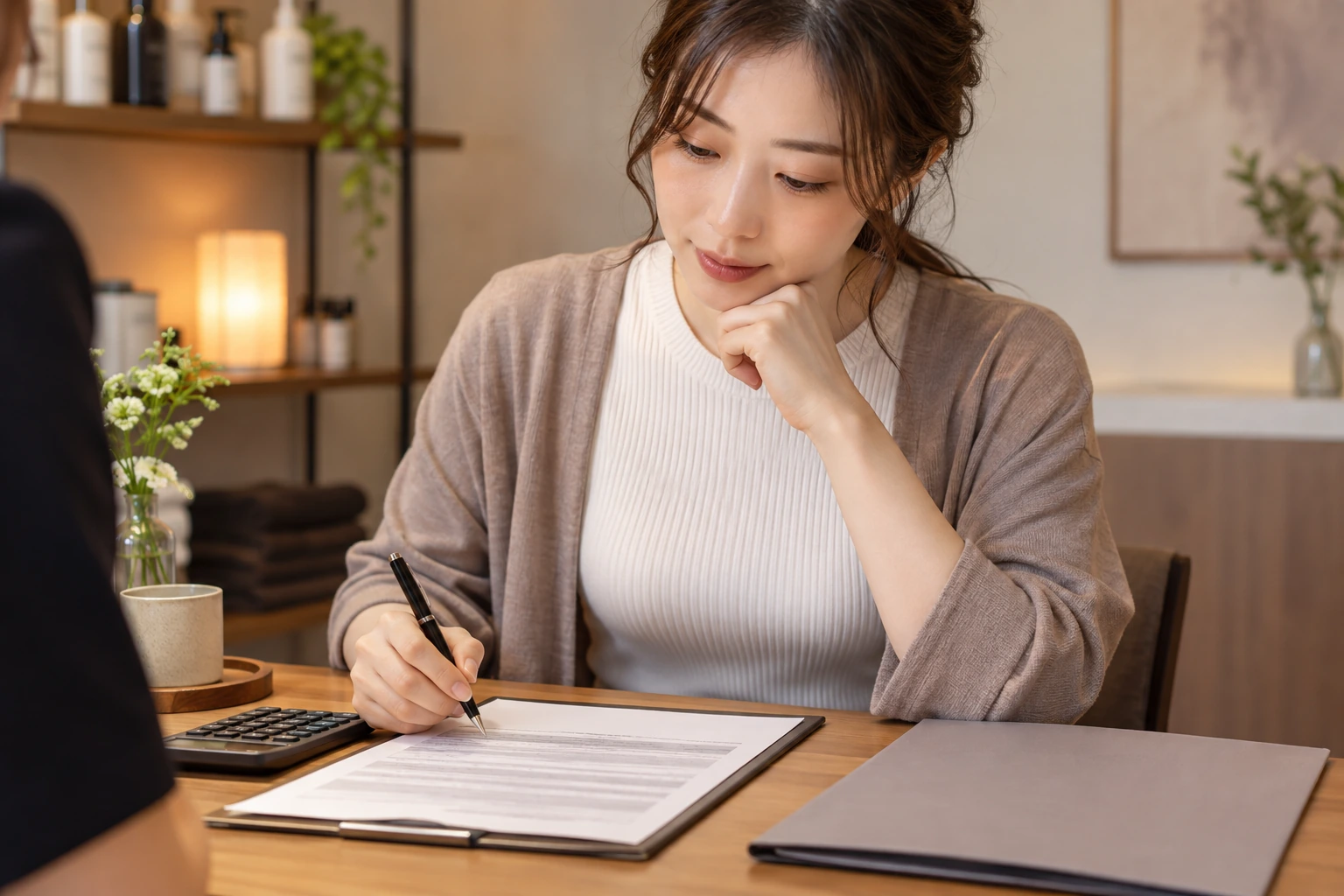 脱毛サロンの契約書面と電卓を前に契約を考える日本人女性