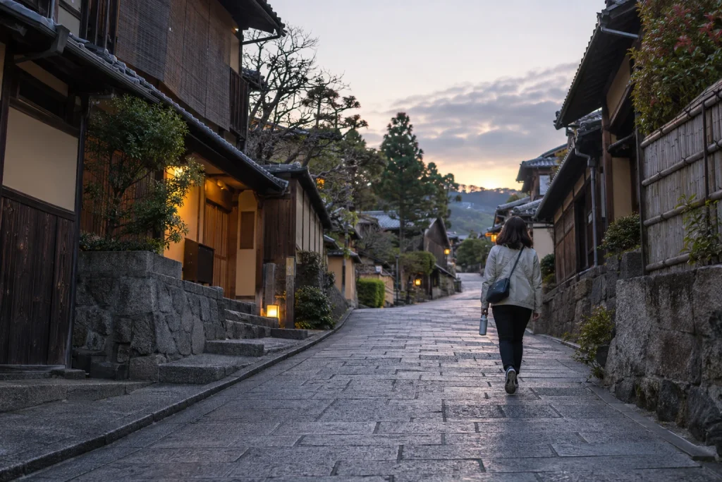 店が開く前の架空の東山の石畳を小さなバッグで上る女性