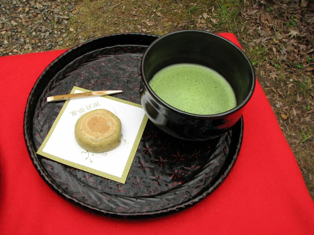 黒い茶碗の抹茶と丸い和菓子をのせた盆