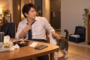 四泊の出張から帰り、夜の食卓と旅行鞄の間で立ち止まる裕介さんと猫