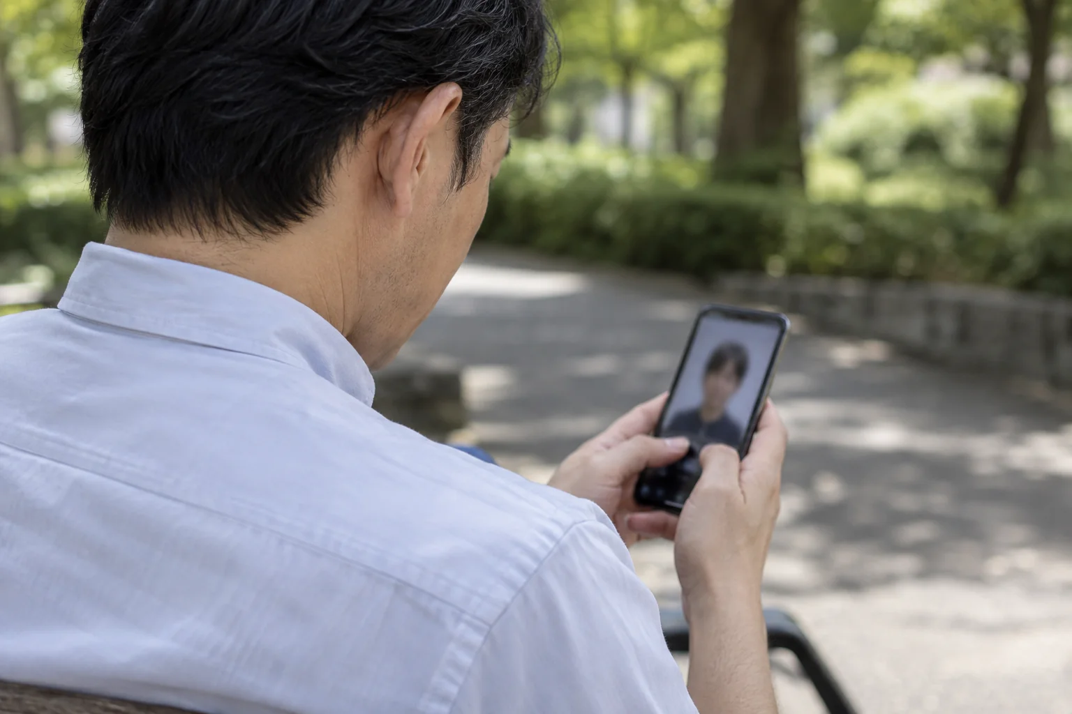 40代の日本人男性が屋外で現在の写真を確認する