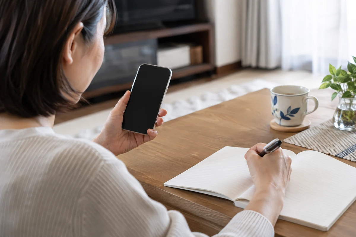 繰り返しの電話を受けた日時と担当者をノートへ控える手元
