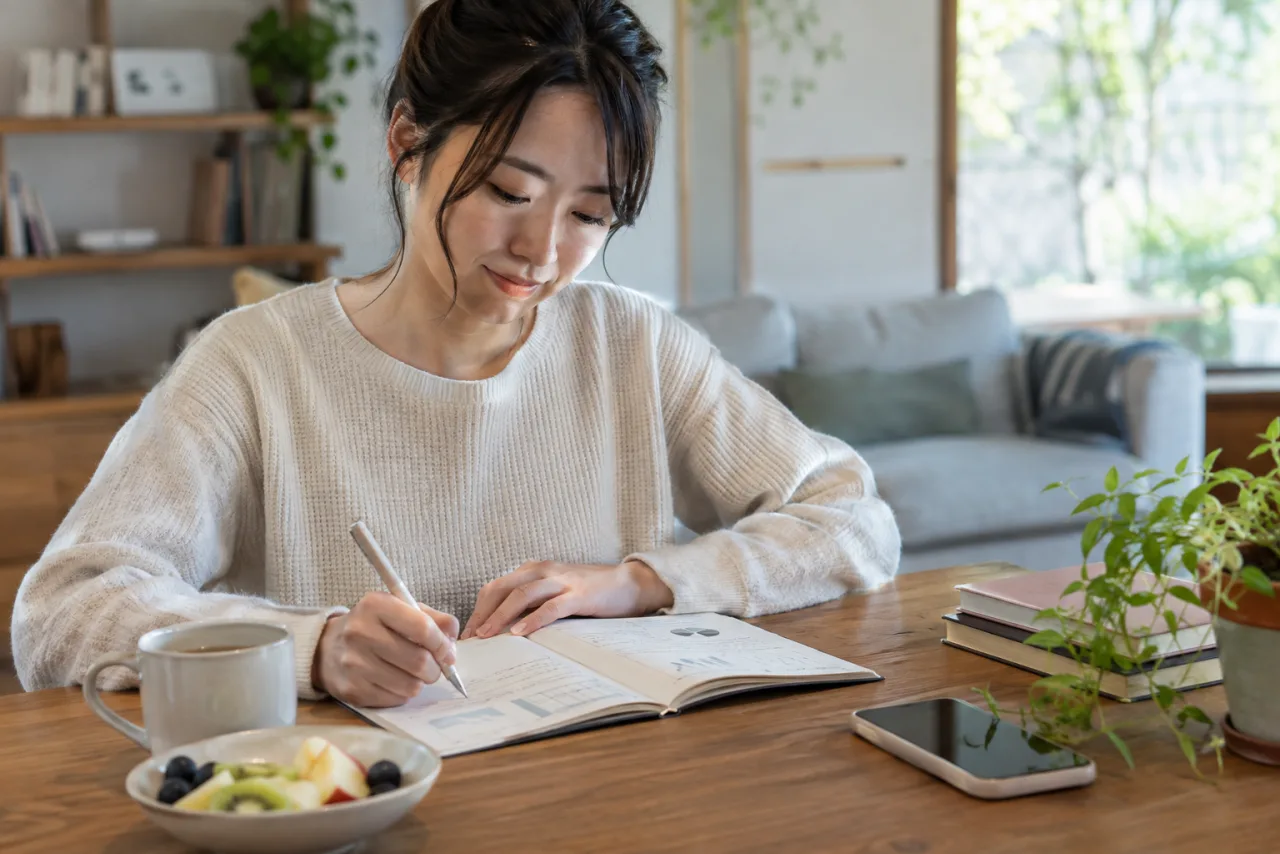 生活の変化と体調をノートに記録する日本人女性
