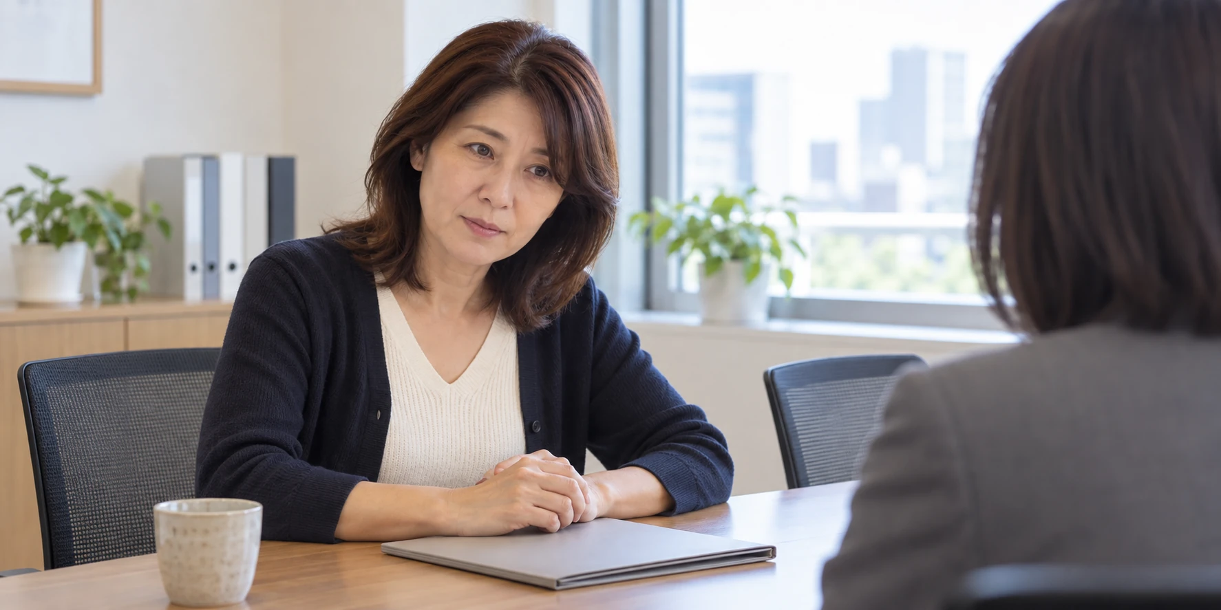 机を挟んで相手と向き合う女性