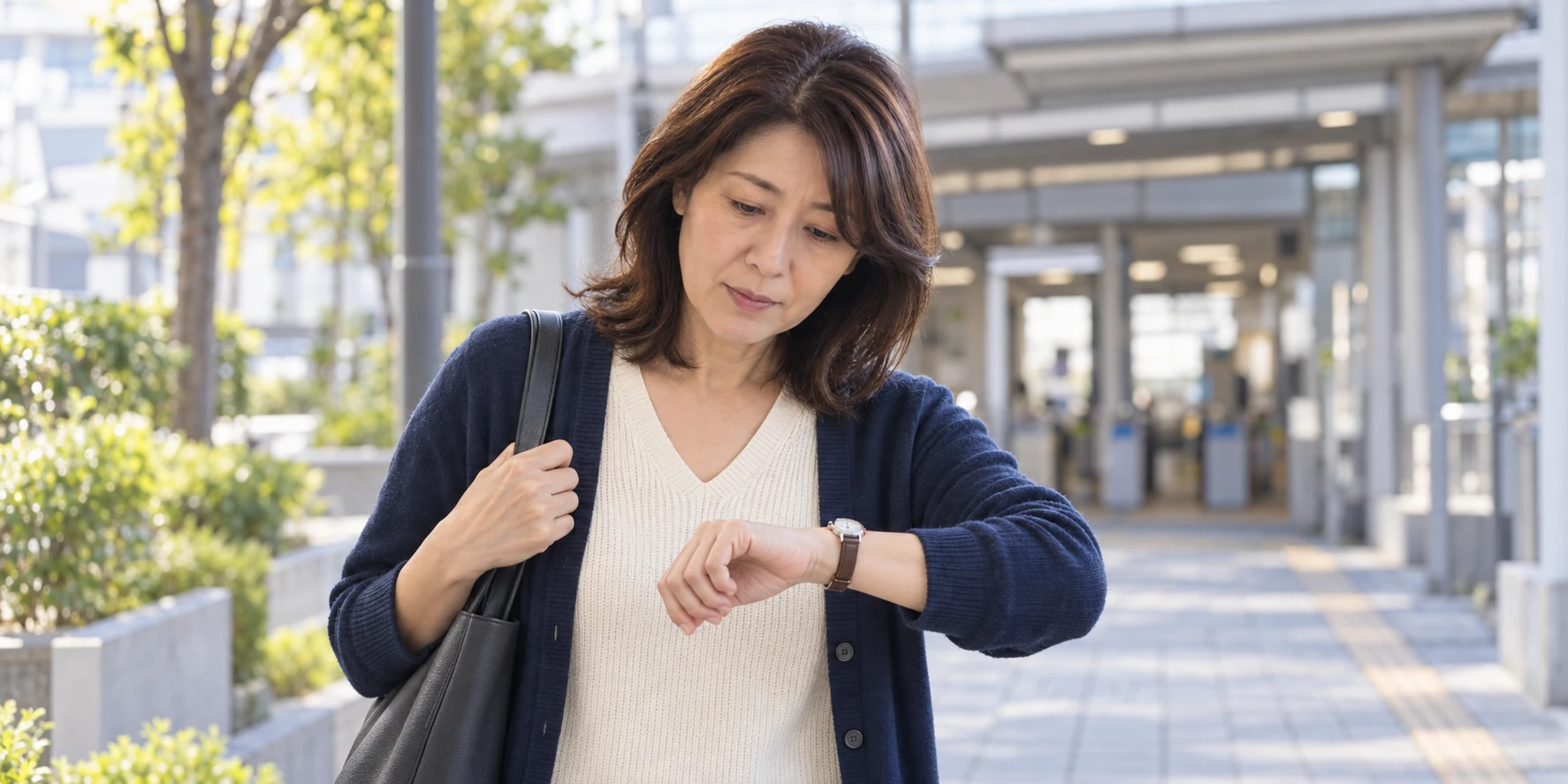 屋外でバッグを肩に掛け、腕時計を見る女性