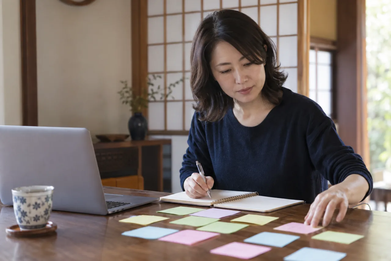 40歳前後の女性が2つの求人書類とカレンダーを見比べている様子