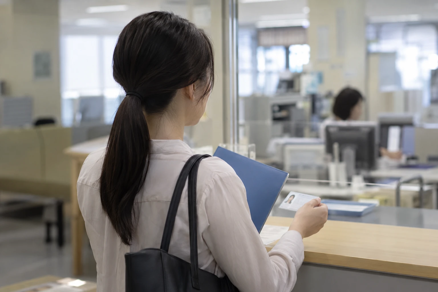 会社の担当者に雇用保険の資格取得手続きを確認する女性
