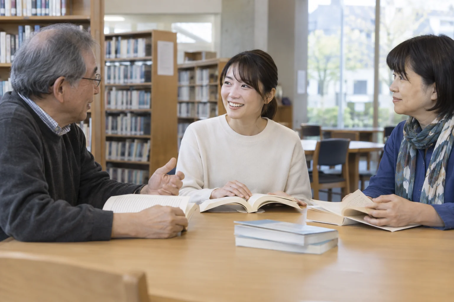 日本人女性が図書館で年代の異なる二人と読書会に参加している