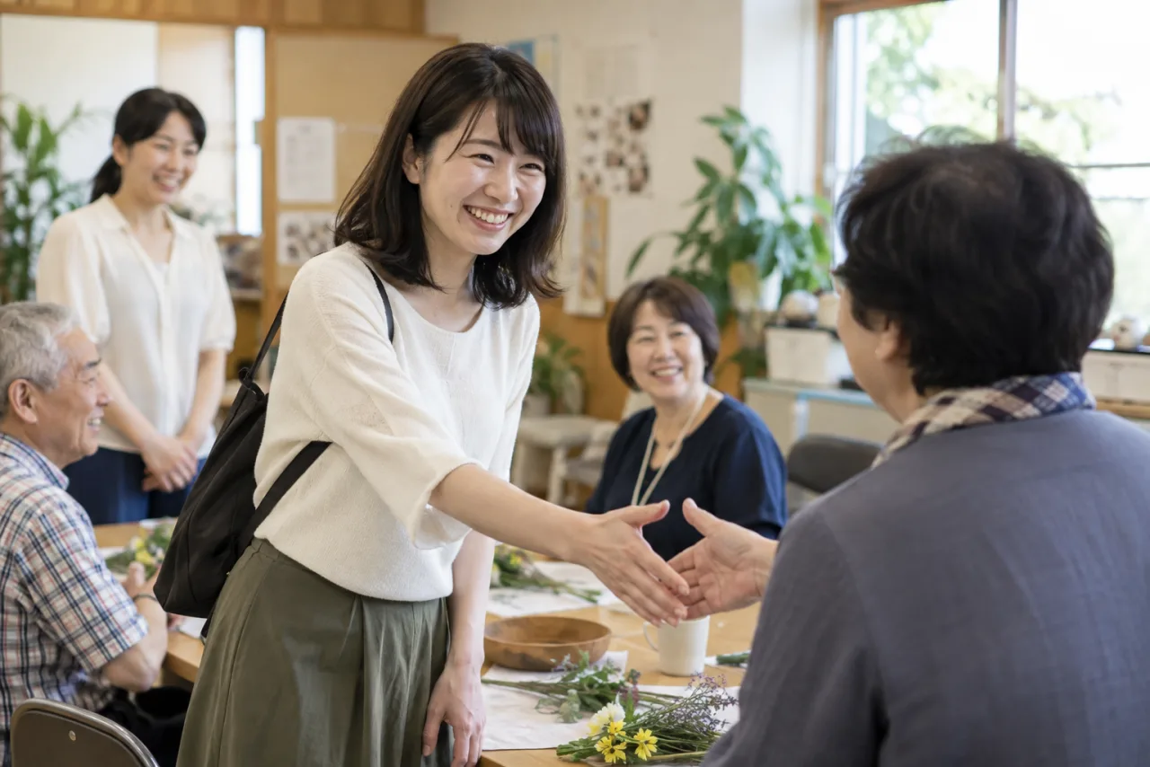 日本人女性が小規模な地域の集まりで挨拶をする