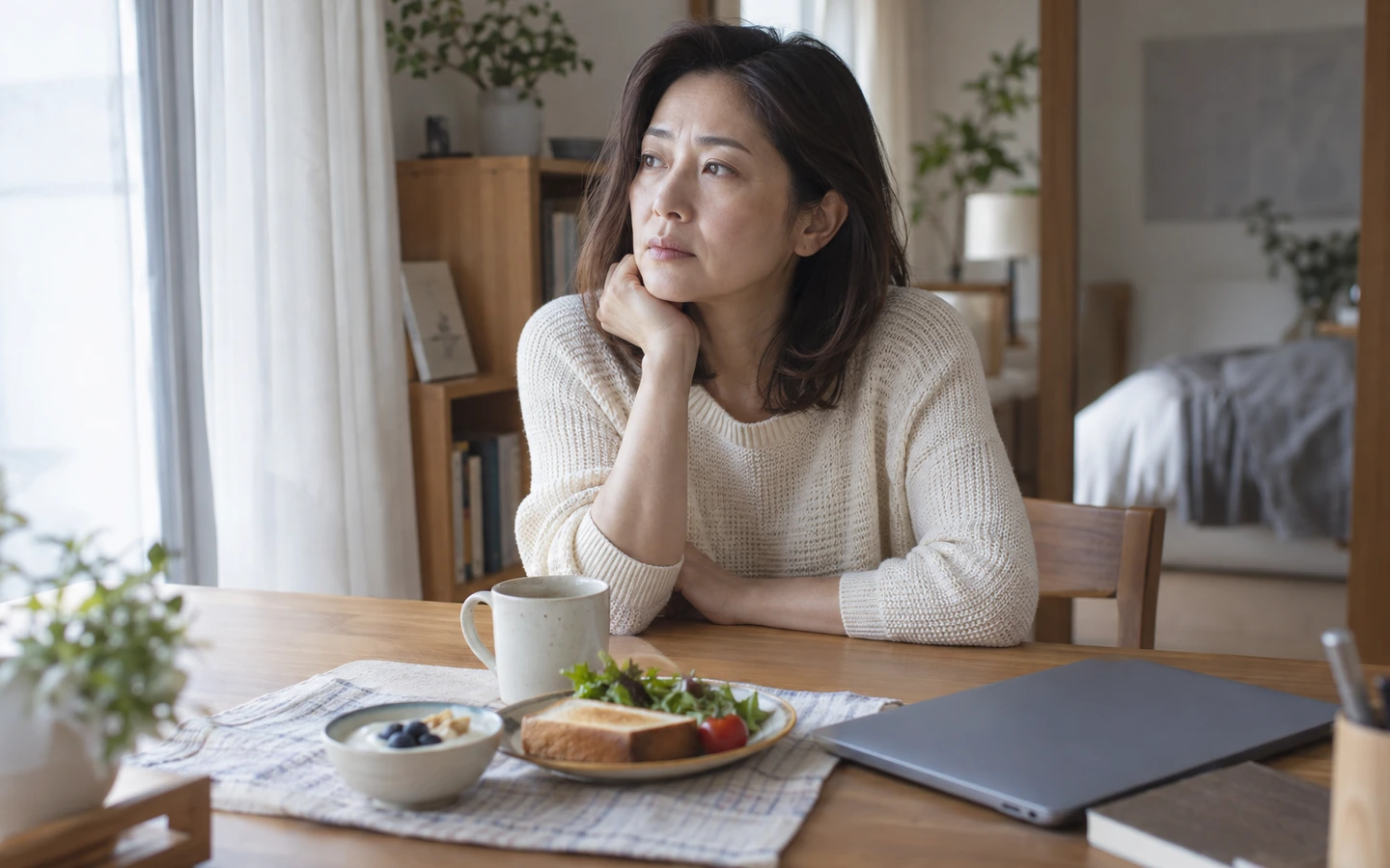 寂しさを感じる日に朝食を前に考え込む女性のイメージ