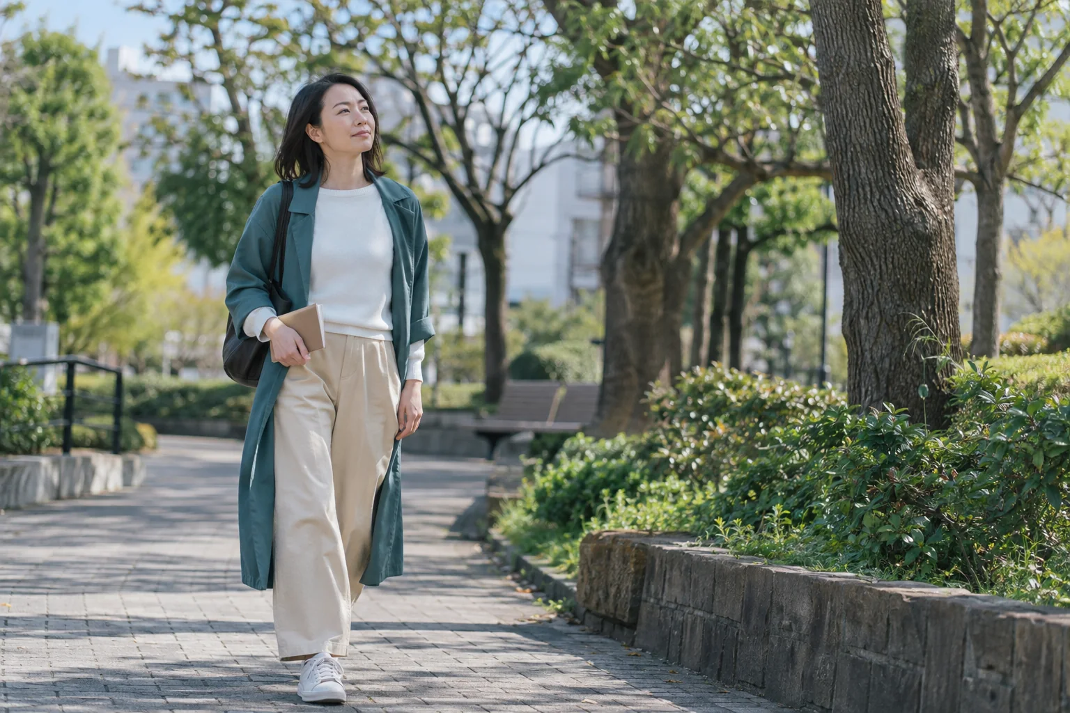 公園を歩きながら自分の次の一歩を落ち着いて考える日本人女性の編集イメージ