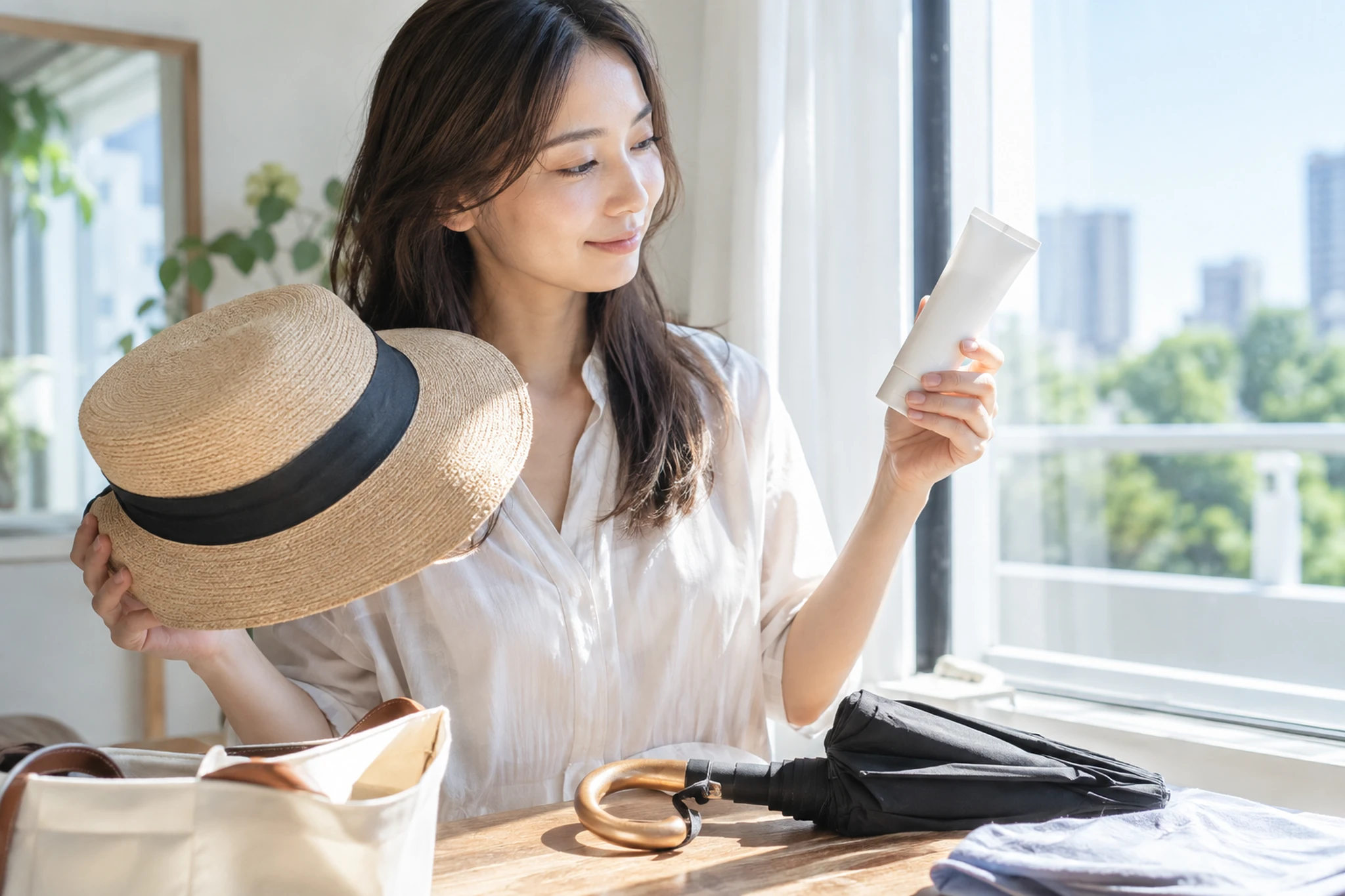 帽子や日傘と無地の日焼け止めを外出前に選ぶ女性
