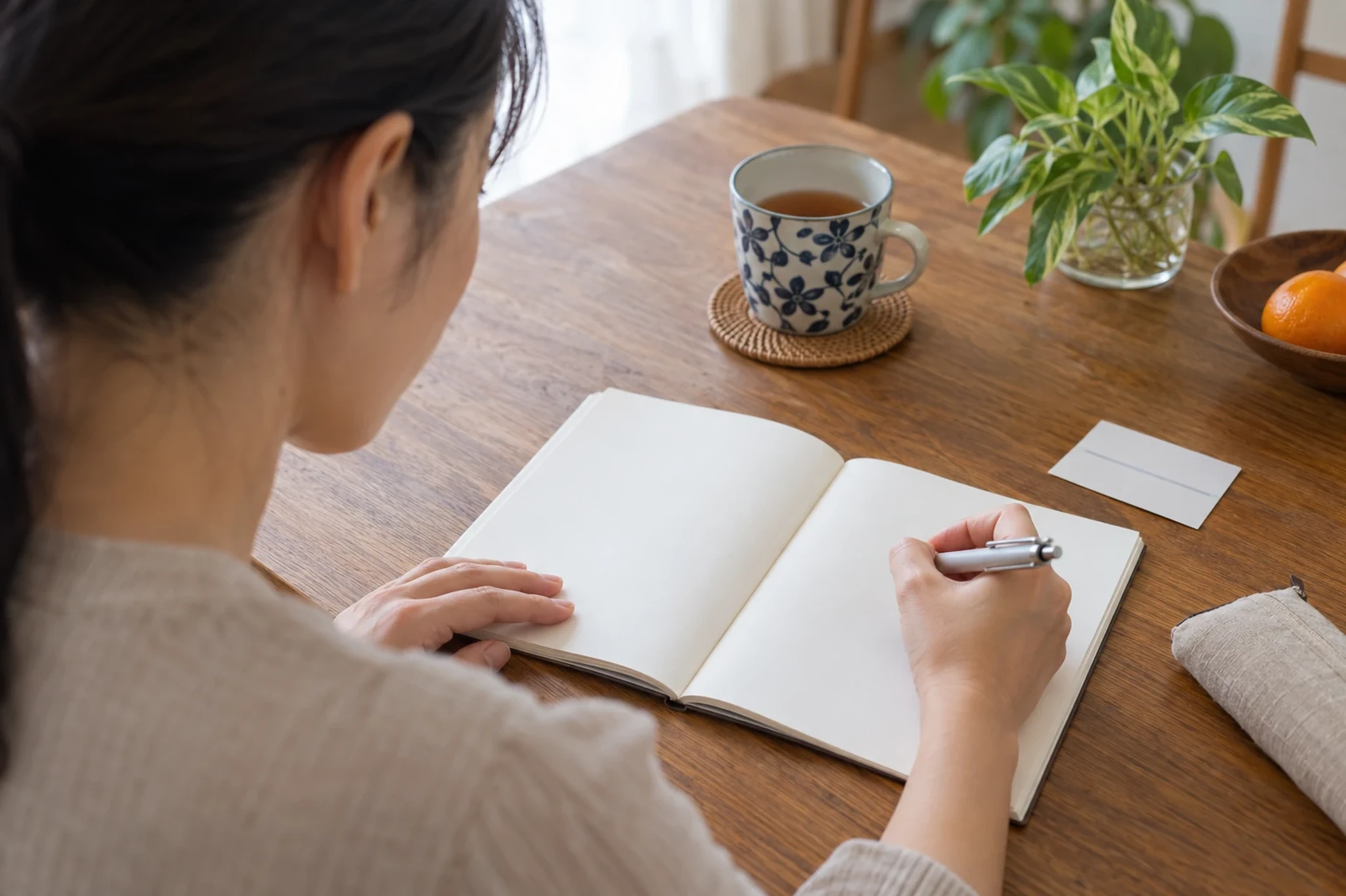 一人暮らしの女性が白紙のノートに医療について考えを書いている様子
