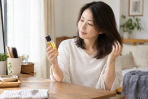 一人暮らしの女性が髪質とヘアオイルを見比べている様子