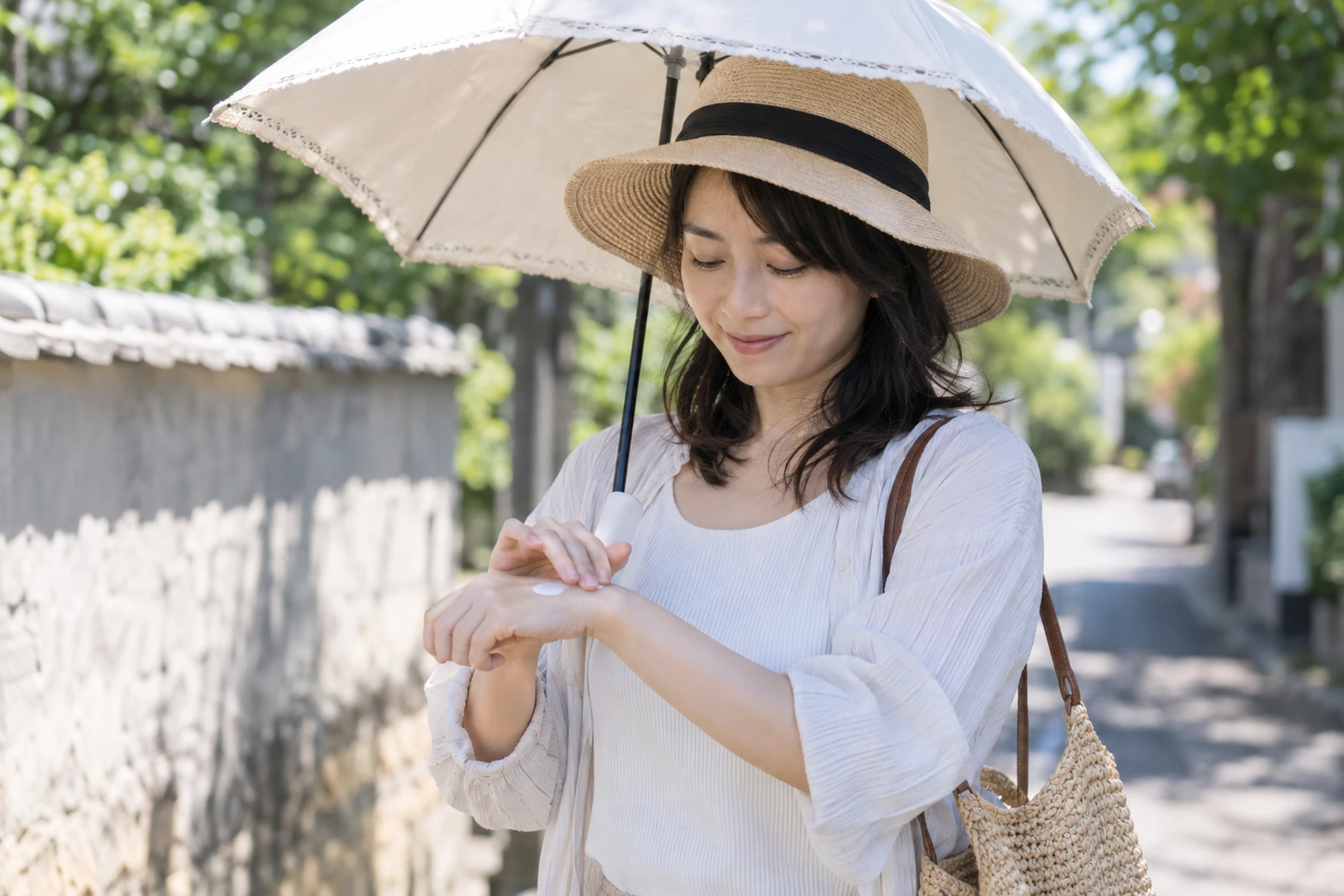 外出先で日焼け止めを塗り直す女性