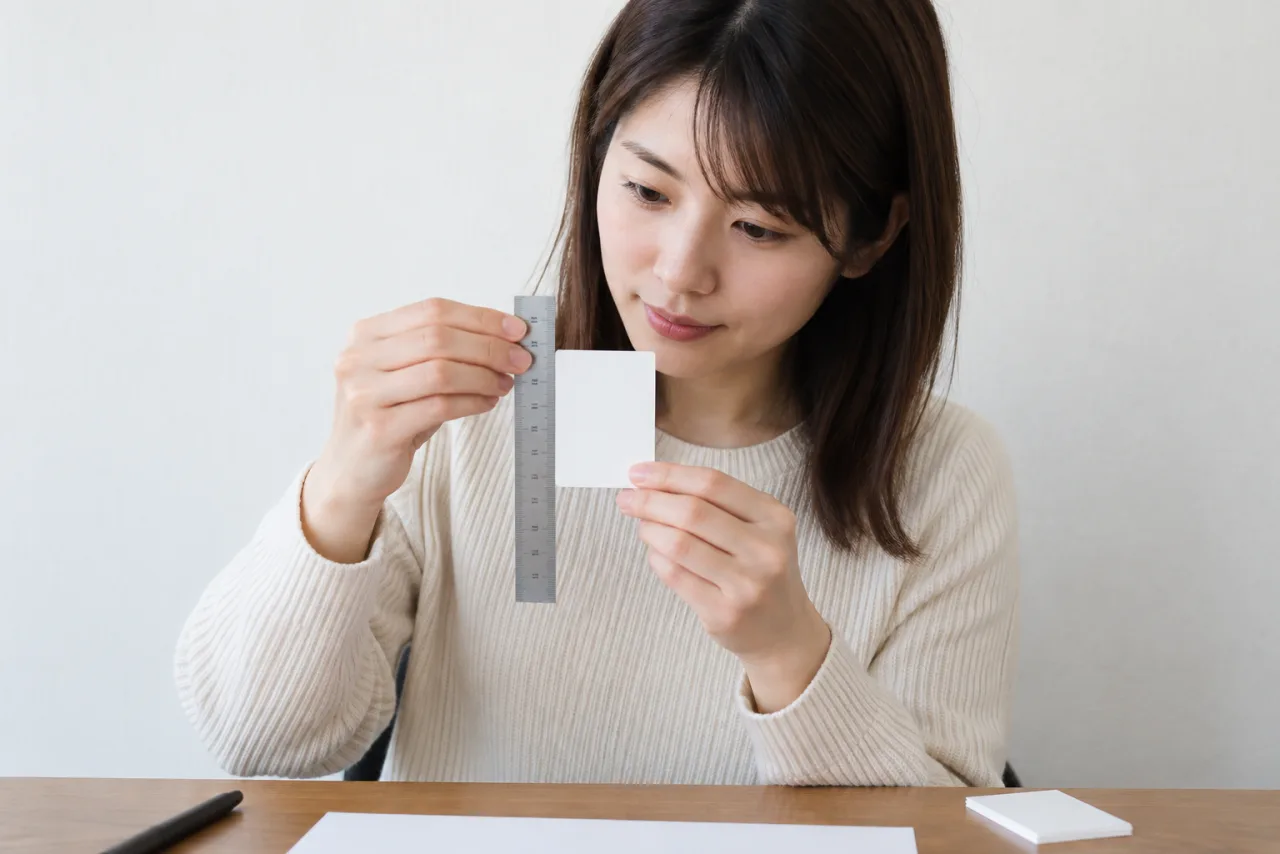 日本人女性が証明写真のサイズを定規で確認している場面