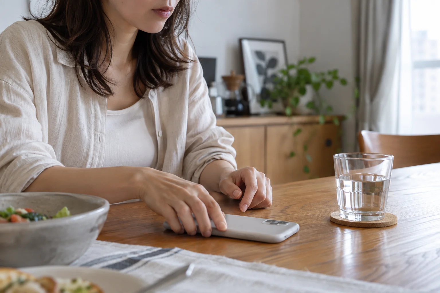 日本人女性が食卓でスマートフォンを伏せる
