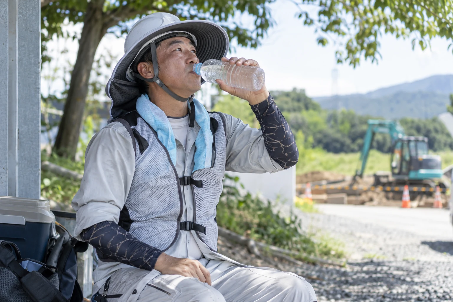 暑さ対策の服装で水分を取る日本人作業者